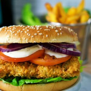 Delicious crispy chicken burger topped with fresh lettuce, tomato, onion, and a creamy sauce.