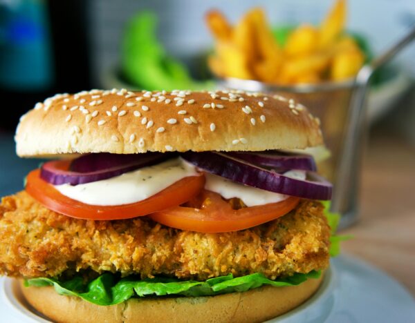 Delicious crispy chicken burger topped with fresh lettuce, tomato, onion, and a creamy sauce.