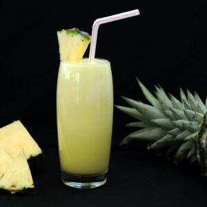 A tropical glass of fresh pineapple juice garnished with a slice and straw, perfect for summer refreshment.