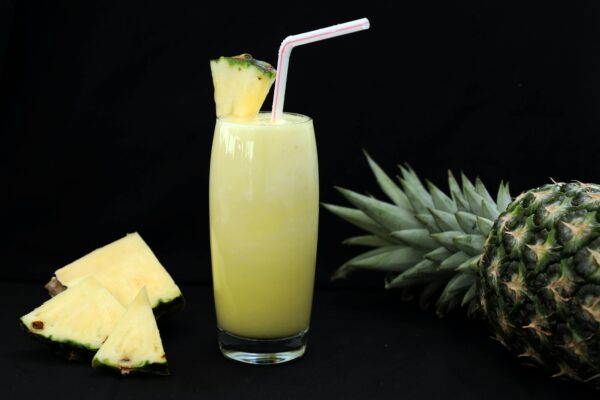 A tropical glass of fresh pineapple juice garnished with a slice and straw, perfect for summer refreshment.