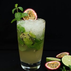 A close-up of a refreshing passion fruit mojito garnished with mint and lime, perfect for a summer day.