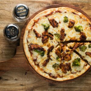 Mouth-watering chicken and broccoli pizza shot from above on a rustic wooden background.