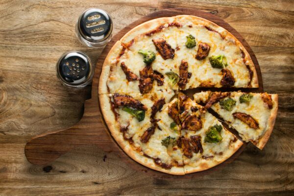 Mouth-watering chicken and broccoli pizza shot from above on a rustic wooden background.