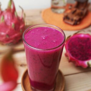 Vibrant dragon fruit smoothie in a glass with fresh fruits, perfect summer refreshment.