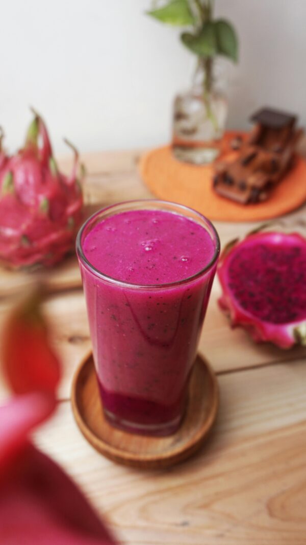 Vibrant dragon fruit smoothie in a glass with fresh fruits, perfect summer refreshment.