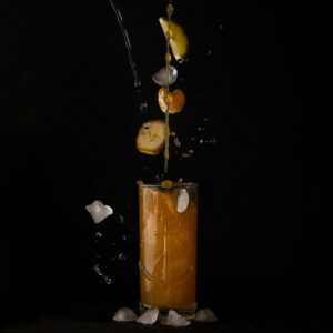 Citrus juice splashes with ice cubes and fruit slices against a black background.