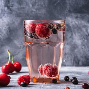 Glass of sparkling water with mixed berries for a refreshing and healthy beverage option.
