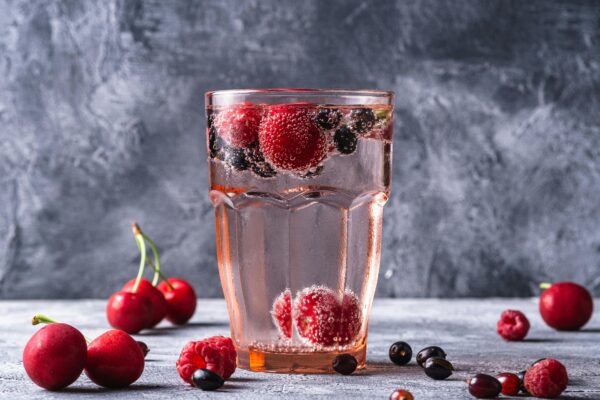 Glass of sparkling water with mixed berries for a refreshing and healthy beverage option.