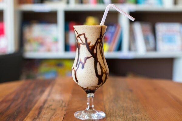 Close-up view of a delicious chocolate milkshake with a straw on a wooden table.