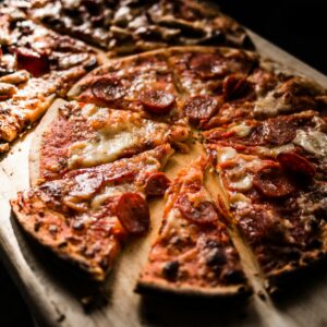 Delicious crispy pepperoni pizza slices on a wooden board, perfect for pizza lovers.