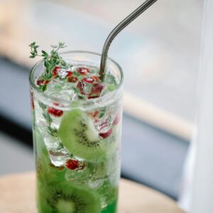 Chilled kiwi and pomegranate cocktail with a metal straw for a refreshing taste.