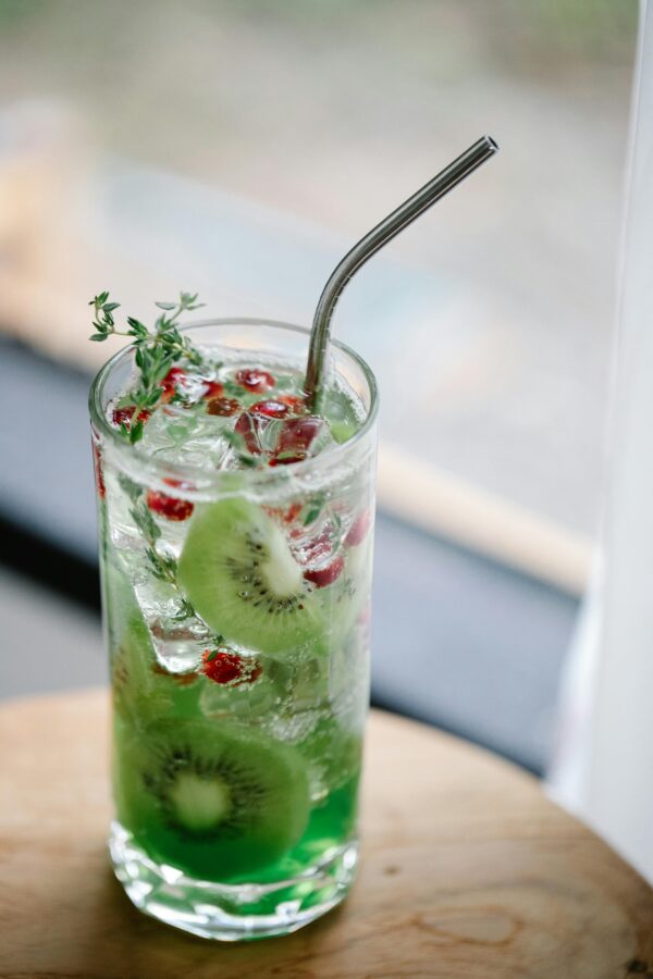 Chilled kiwi and pomegranate cocktail with a metal straw for a refreshing taste.